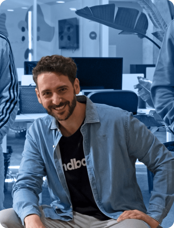 Fer Guirao sonriendo, sentado en una oficina con una camiseta de Landbot